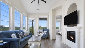 A spacious living room with a fireplace, a large TV mounted above it, and a comfortable seating area with a sofa and armchairs. - Lake & Mountain View Condo - The Cliffs on Indian Point - Silver Dollar City (Branson)