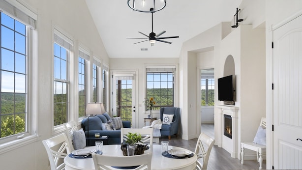 A spacious living room with a fireplace, a ceiling fan, and a television. - Lake & Mountain View Condo - The Cliffs on Indian Point - Silver Dollar City (Branson)