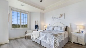 A bedroom with a large bed, a nightstand, a chair, and a window with a view of greenery. - Lake & Mountain View Condo - The Cliffs on Indian Point - Silver Dollar City (Branson)