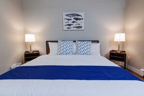 Ein Hotelzimmer mit einem großen Bett, zwei Nachttischen mit Lampen, einem an der Wand hängenden Bild von Fischen und einer blauen Bettdecke.