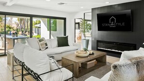 A modern living room with a large sectional sofa, a coffee table, and a flat-screen TV mounted on the wall. - SWSS 7BR Estate | Golf Sim | Sauna | Pool | Hot Tub | Putting Green | Volleyball | Games (Scottsdale)