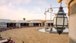 Ein Wüstenresort mit Außenbereich, Sitzgelegenheiten, Zelten, einem Wasserspiel und einer traditionellen Laterne.
