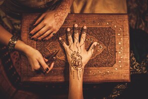 Una mesa de madera con intrincados grabados y una mano con diseños de henna.