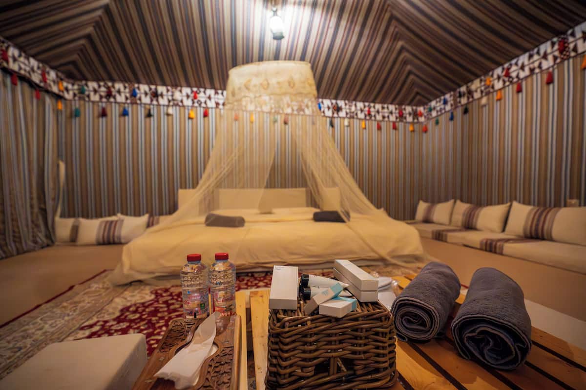 Una habitación con cama, una cesta de mimbre, artículos de aseo y una manta.