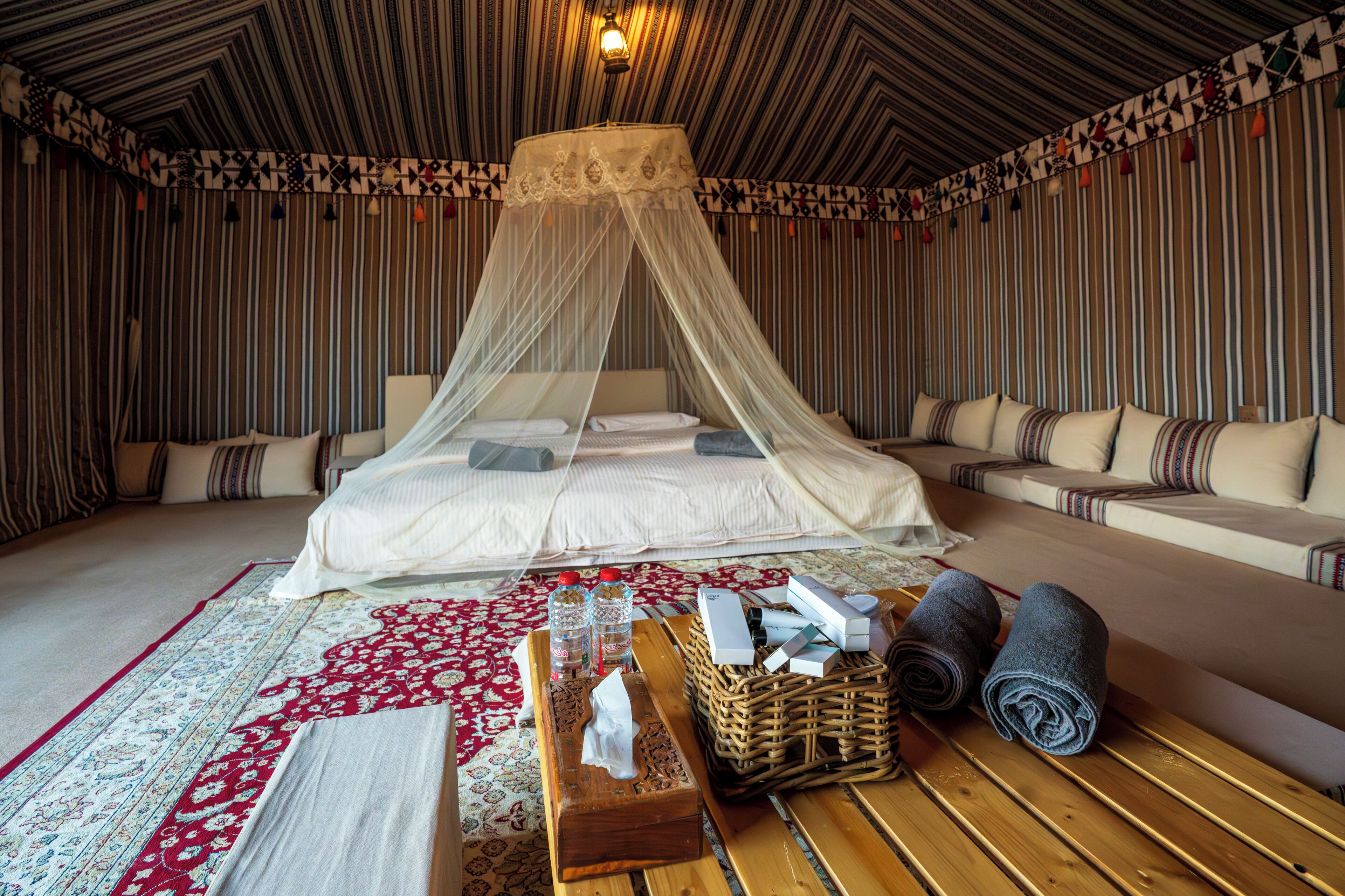 Une pièce comprenant un lit, un canapé, une table en bois et un tapis à motifs.