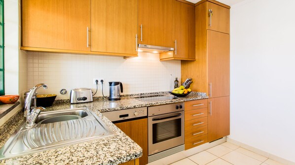 A kitchen with wooden cabinets, a granite countertop, stainless steel appliances, and a sink.