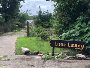 Discover the serene entrance to Little Linney, surrounded by lush greenery and a variety of plants.