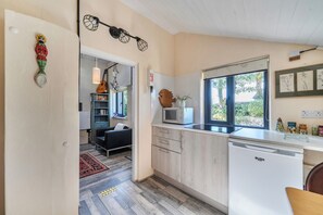 A compact kitchen with a microwave, a sink, and a window with a view of greenery. - Little Linney - Sleeps 2 - Garden - Parking - Wifi (Bideford)
