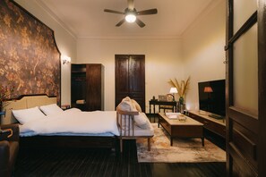A hotel room with a bed, a chair, a desk, a TV, and a wardrobe.