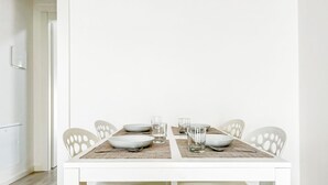 Una mesa de comedor con sillas blancas y mantel blanco.