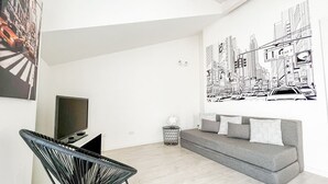 Una sala de estar moderna con un sofá gris, un sillón negro y un gran mural con vistas a la ciudad.