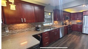 Una cocina moderna con armarios de madera oscura, un refrigerador de acero inoxidable, un microondas y un horno empotrado.
