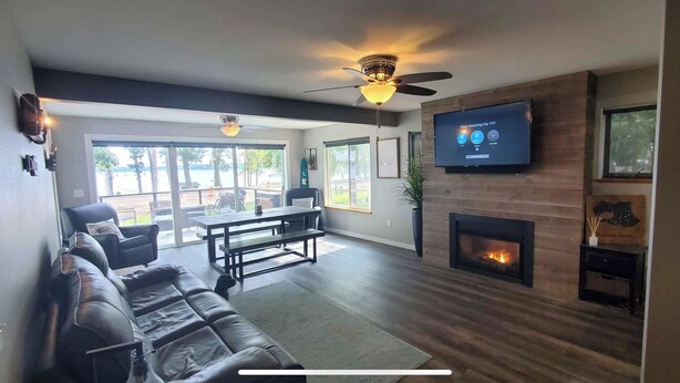 Una sala de estar moderna con chimenea, un televisor montado en la pared y un ventilador de techo.
