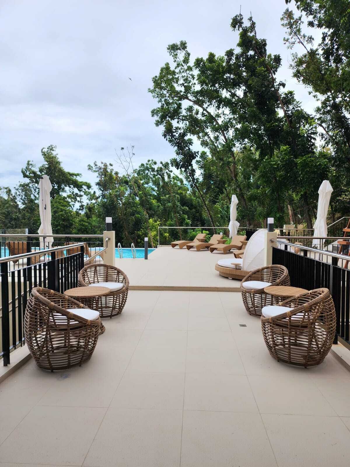 A poolside area with wicker chairs and a pool.