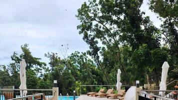 A poolside area with wicker chairs and a pool.