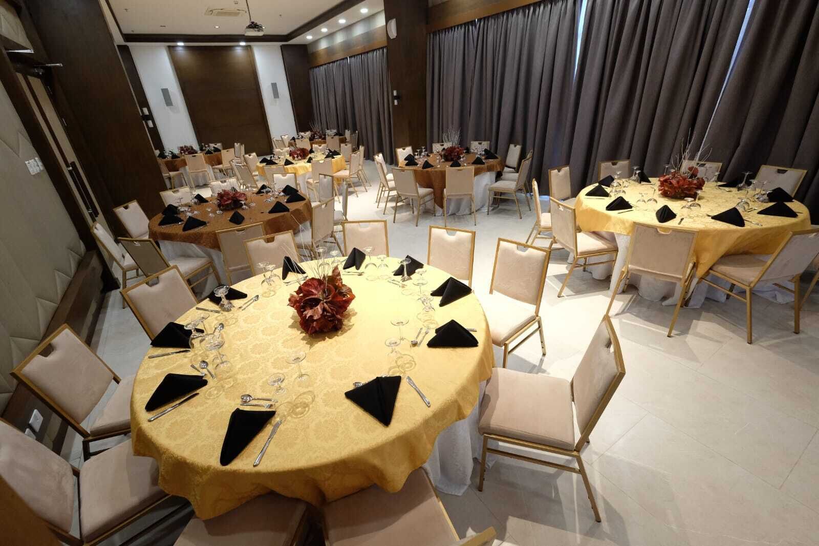 A conference room with multiple round tables, each set with chairs, centerpieces, and table settings.