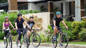 Four people riding bicycles in front of a building with a sign that reads "Hotel".