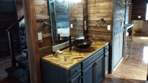 A wooden interior with a wooden countertop, a sink, and a mirror. - Private, rustic country home with hot tub, movie theater and a view (Pineville)