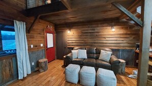 A cozy room with a leather sofa, wooden walls, and a view of a snowy landscape. - Private, rustic country home with hot tub, movie theater and a view (Pineville)