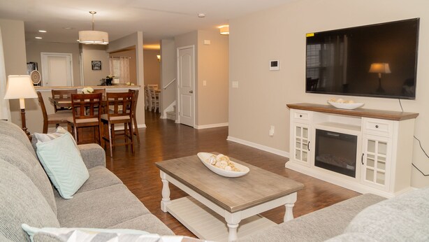 A living room with a sofa, coffee table, TV, fireplace, and dining area. - Beautiful spacious 4 bedroom house , sleeps 10+ (Raleigh)