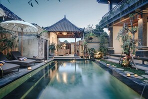 A serene pool area with lounge chairs, a gazebo, and lush greenery. - Sitala Suite (Ubud)