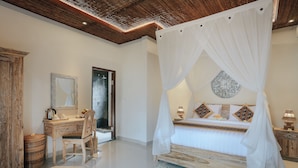 A bedroom with a canopy bed, a wooden desk, a chair, and a mirror. - Sitala Suite (Ubud)
