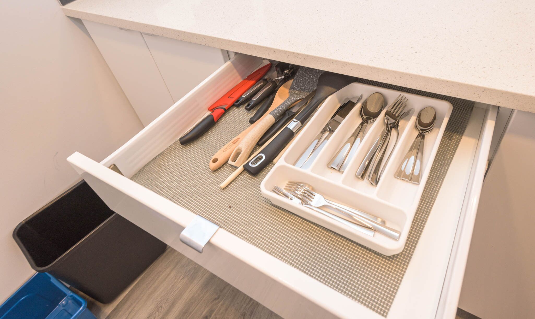 A drawer with various kitchen utensils and tools, including knives, spoons, and a spatula.
