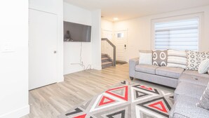 A modern living room with a grey sofa, patterned cushions, and a geometric rug. - Luxury and Comfort Combined. (Edmonton)