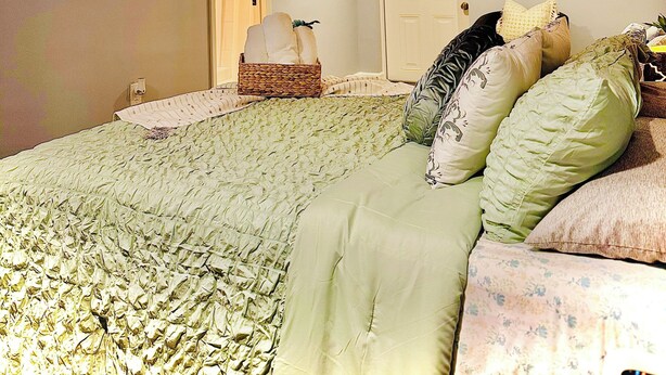 A bedroom with a bed, a television, and artwork on the walls.
