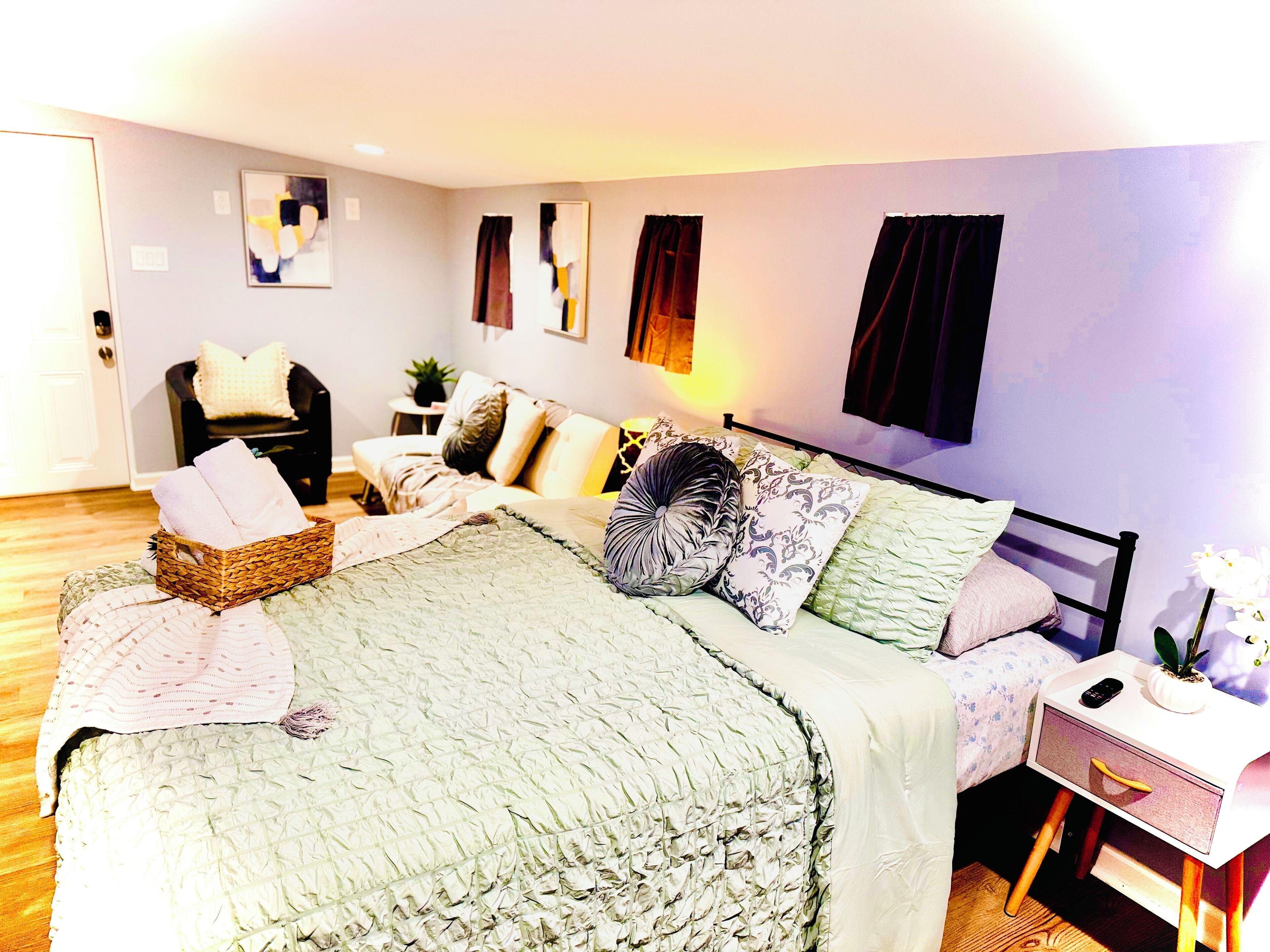 A bedroom with a bed, bedside table, nightstand, and a chair.