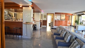 A hotel lobby with a reception desk, a bar area, and a seating area with patterned cushions. - Hotel Orizzonti (Rimini)
