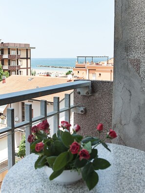 Enjoy the breathtaking view of the coastal area from this balcony, featuring a potted plant and a metal railing.