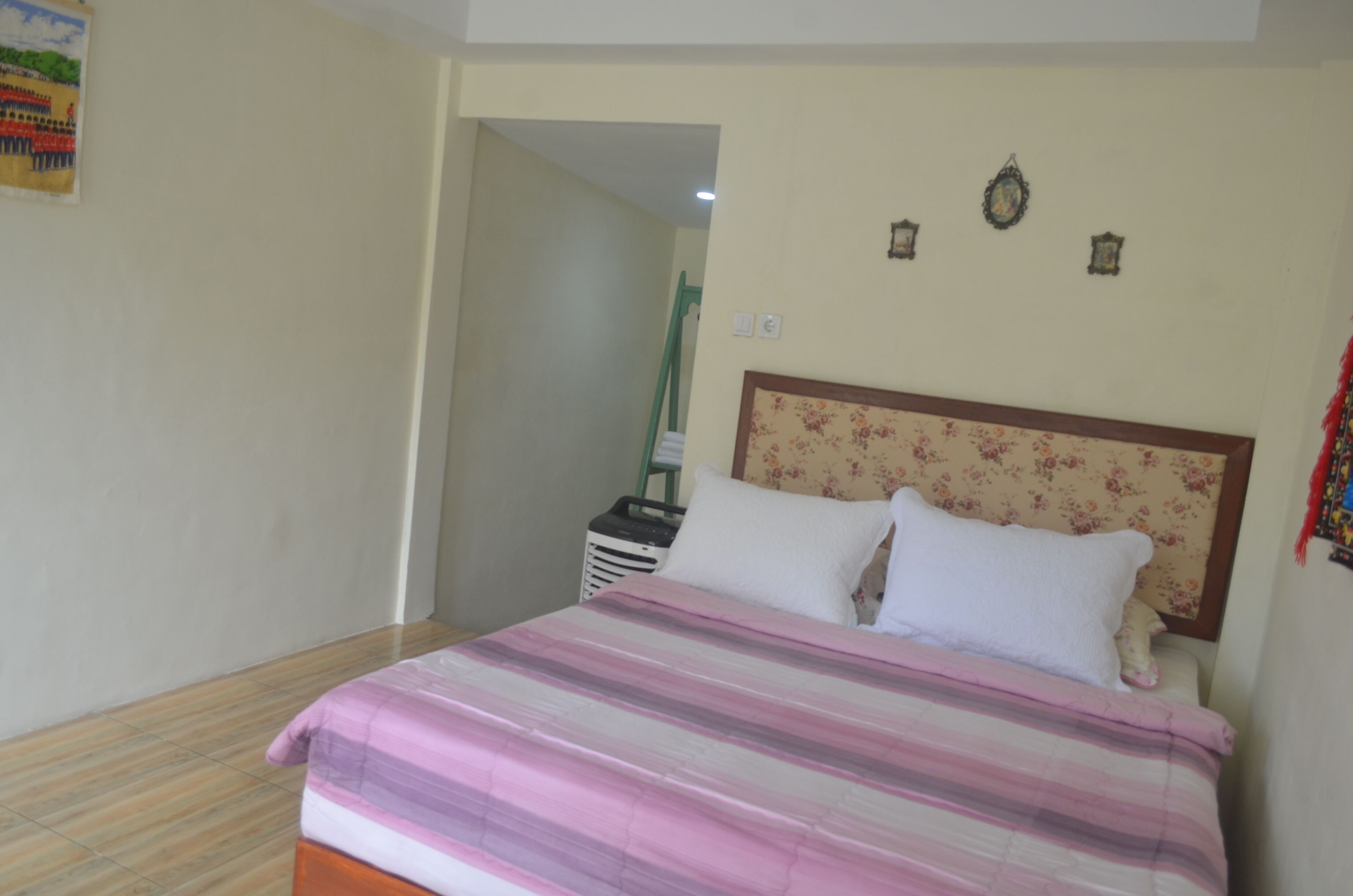 A bedroom with a bed, a nightstand, and a wall-mounted light fixture.