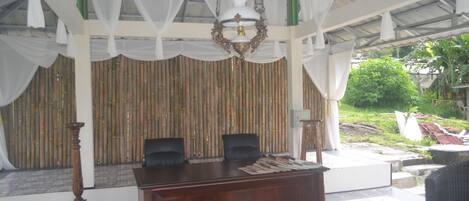A reception area with a wooden desk, two black chairs, and a hanging chandelier.