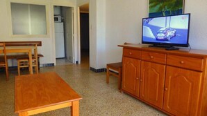 A room with a wooden table, a TV on a wooden cabinet, and a door leading to another room. - Cye 5 Rentalmar (Vila-Seca)