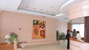 A hotel lobby with a reception desk, a seating area, and a large abstract painting on the wall. - Cye 5 Rentalmar (Vila-Seca)