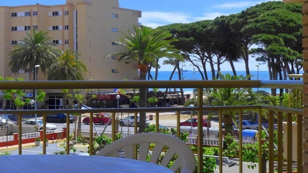 A balcony with a view of a street, palm trees, and a building. - Cye 5 Rentalmar (Vila-Seca)