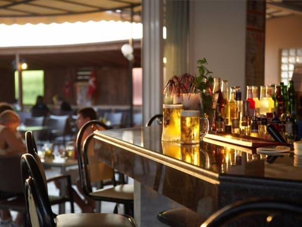 Una zona de bar con una barra, varias botellas y una jarra de cerveza.