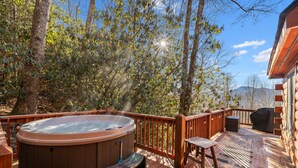 En træterrasse med jacuzzi, et bord og grillområde.