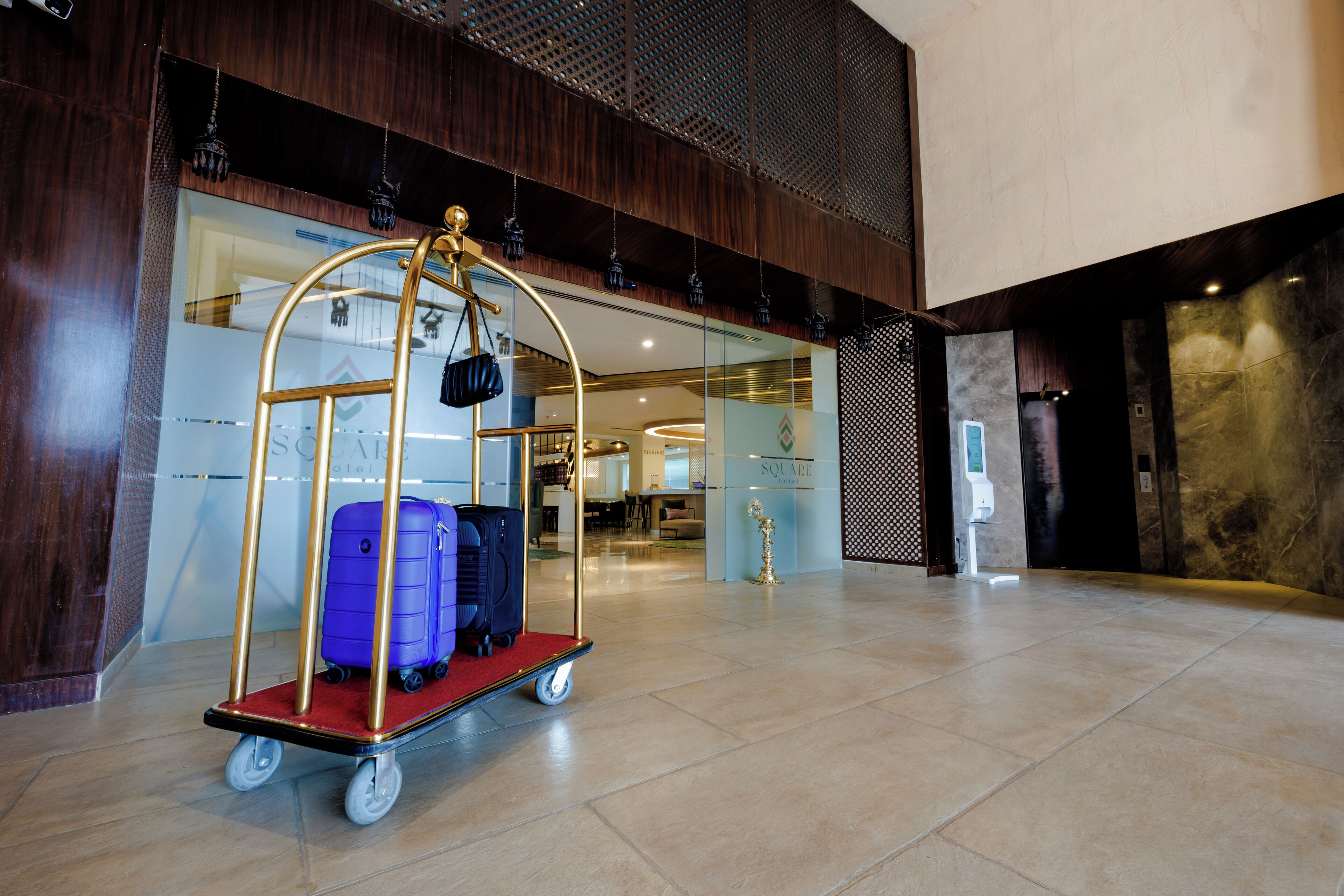 A luggage cart with suitcases in a hotel lobby.