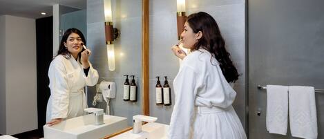 Un baño moderno con un espejo grande, un lavamanos blanco y un perchero para toallas.