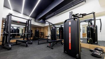 Un gimnasio con equipo de levantamiento de pesas, bancos y un espejo.