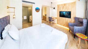 Quarto de hotel moderno com uma cama grande, uma escrivaninha, uma cadeira, uma televisão e uma mesa pequena.