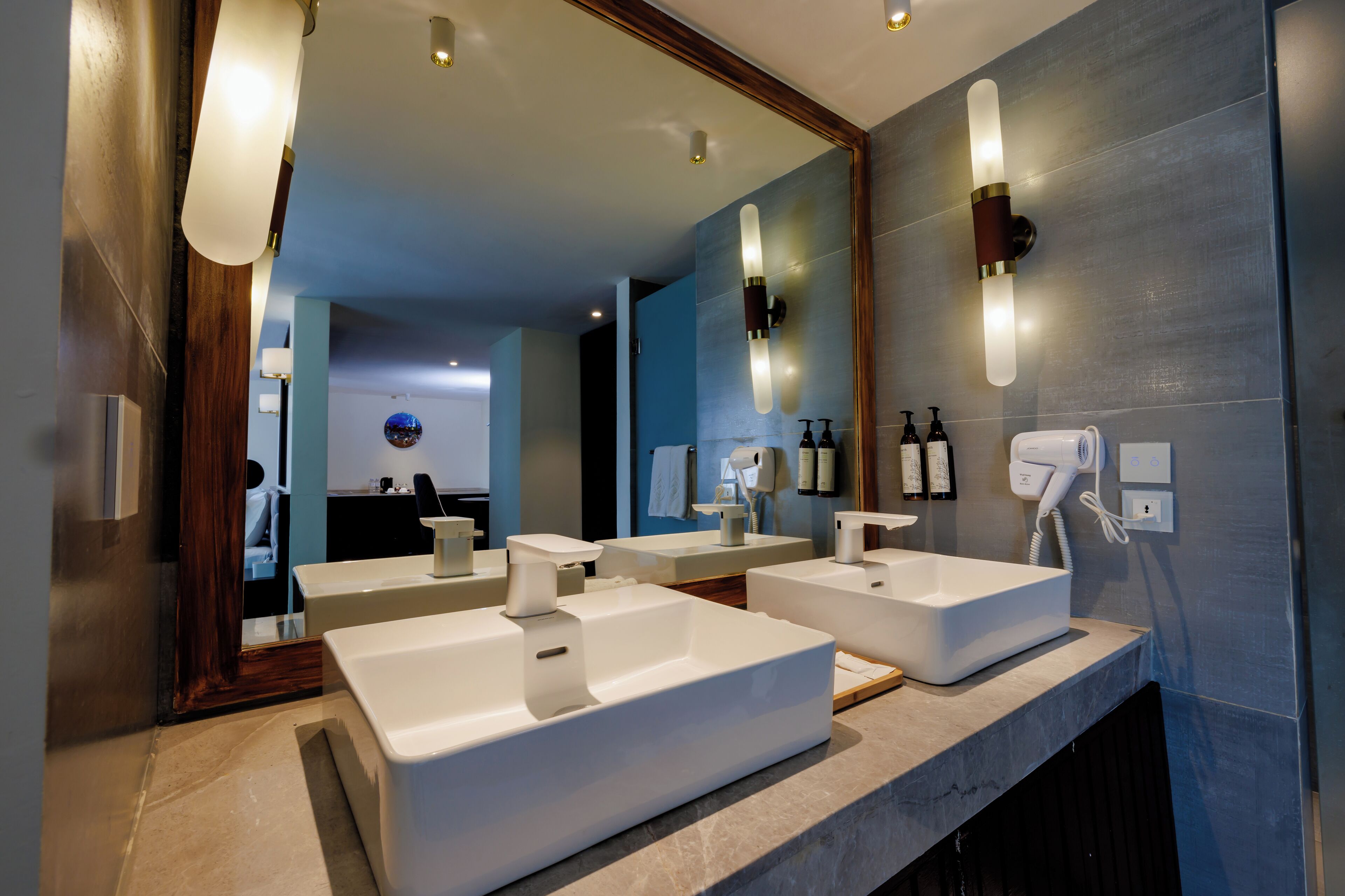 A modern bathroom with two sinks, a large mirror, and a hairdryer.