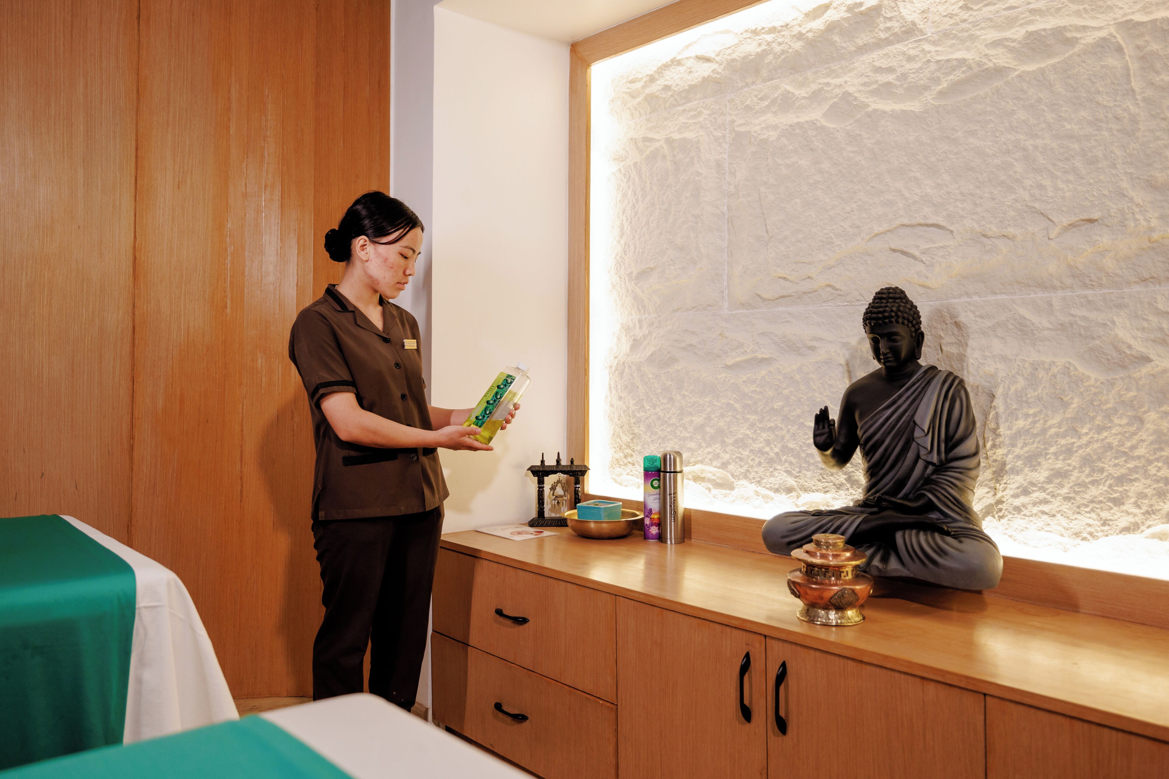 Una habitación con un mueble de madera, una estatua de Buda y una persona sosteniendo una caja.