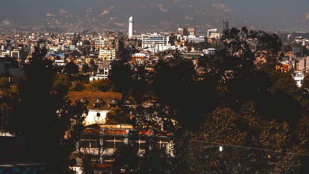 Una piscina con vistas a un paisaje urbano y montañas al fondo.