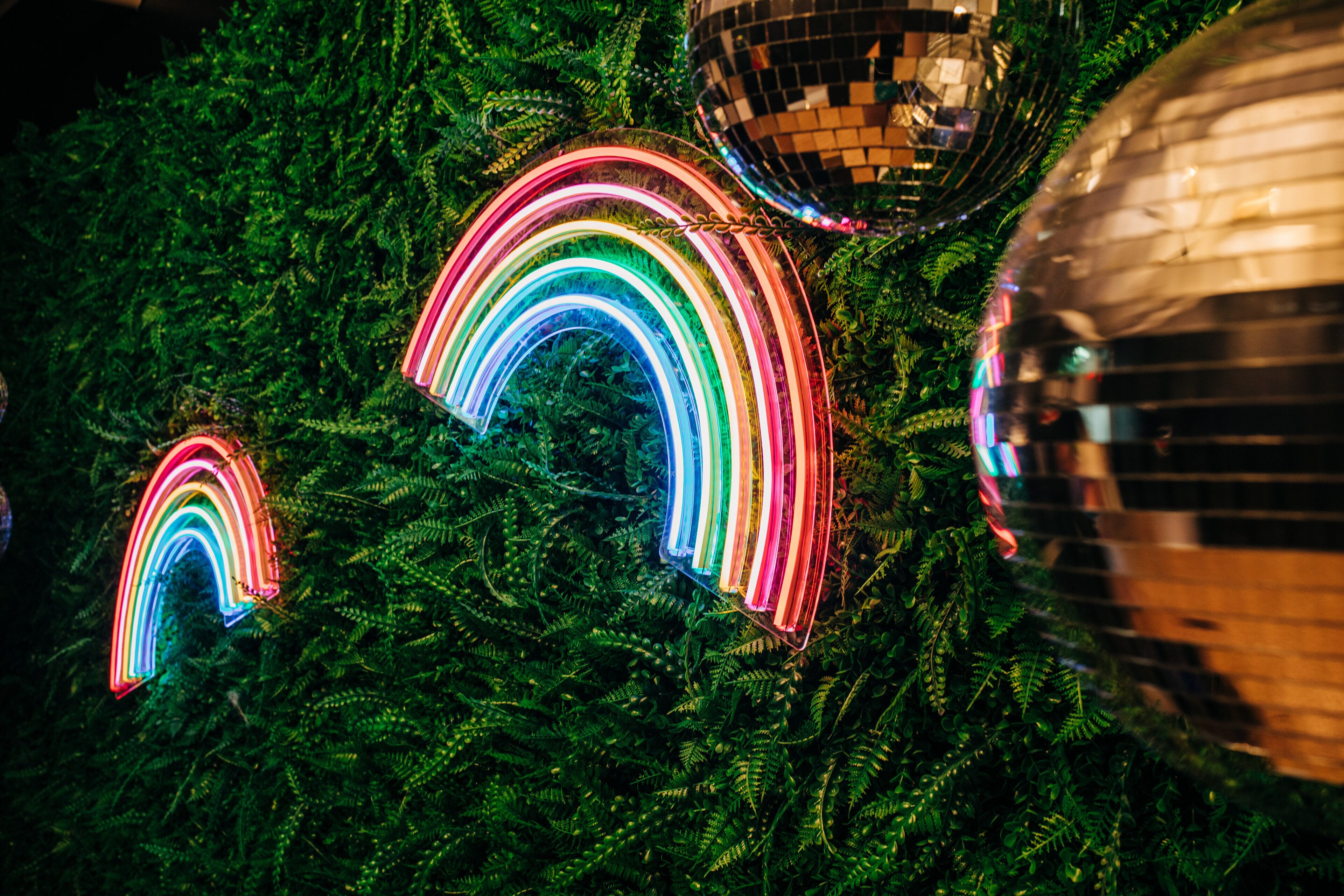 A Christmas tree with neon rainbow lights and disco balls.