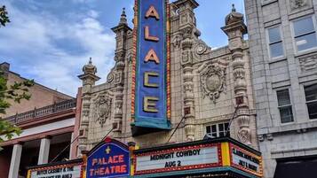 A theater with ornate architecture and a marquee advertising 'Palace Theatre' and 'Midnight Cowboy' showings.