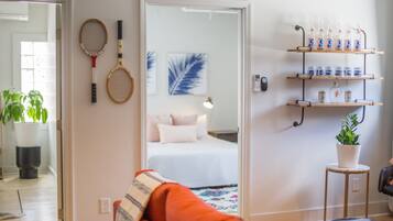 A room with a bed, a mirror, a shelf with bottles, and tennis rackets on the wall.