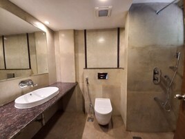 A bathroom with a marble sink, a toilet, and a shower area.